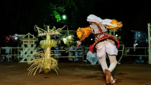 Tradicionāls dejotājs uzstājas nakts pasākumā ar dekoratīviem elementiem brīvā dabā.