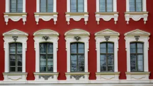 Jelgavas pils arhitektoniskās detaļas ar sarkanu fasādi un baltiem logu rāmjiem Jelgavā.