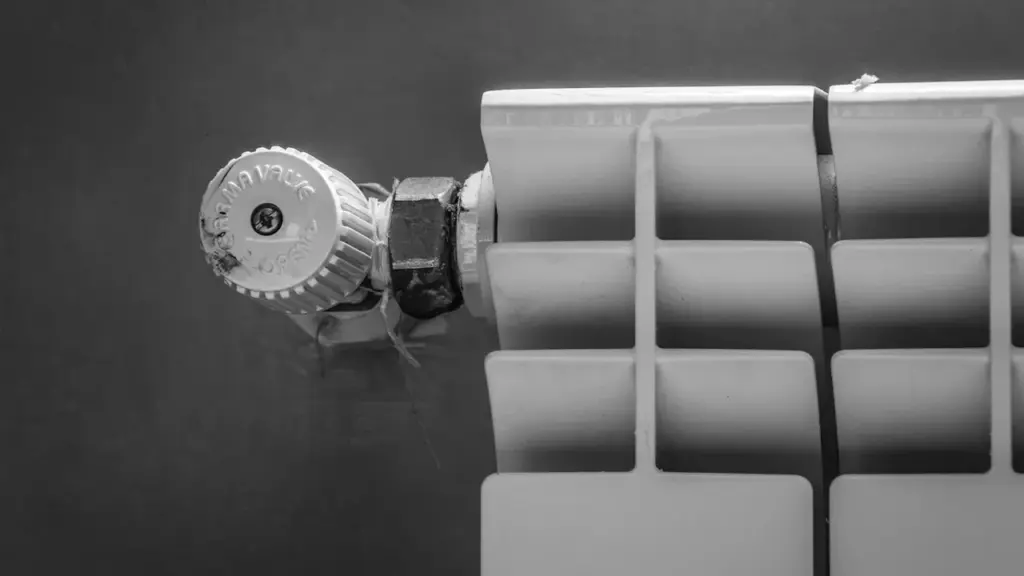 Balts metāla radiators ar termostata ventili gatavojoties apkures sezonas sākumam mājoklī.