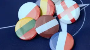 Kolekcija ar dažādu valstu karogu nozīmītēm, kurā redzams arī Latvijas karoga simbols.