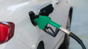 Degvielas uzpildes pistole ievietota baltas automašīnas bākā degvielas uzpildes stacijā