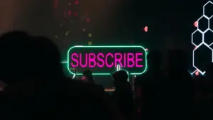 Neon gaismas zīme ar uzrakstu Subscribe tumšā telpā, kas simbolizē tiešsaistes abonementus.