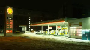 Degvielas uzpildes stacija vakarā, kad cenas uz tablo ir skaidri redzamas un izgaismotas.