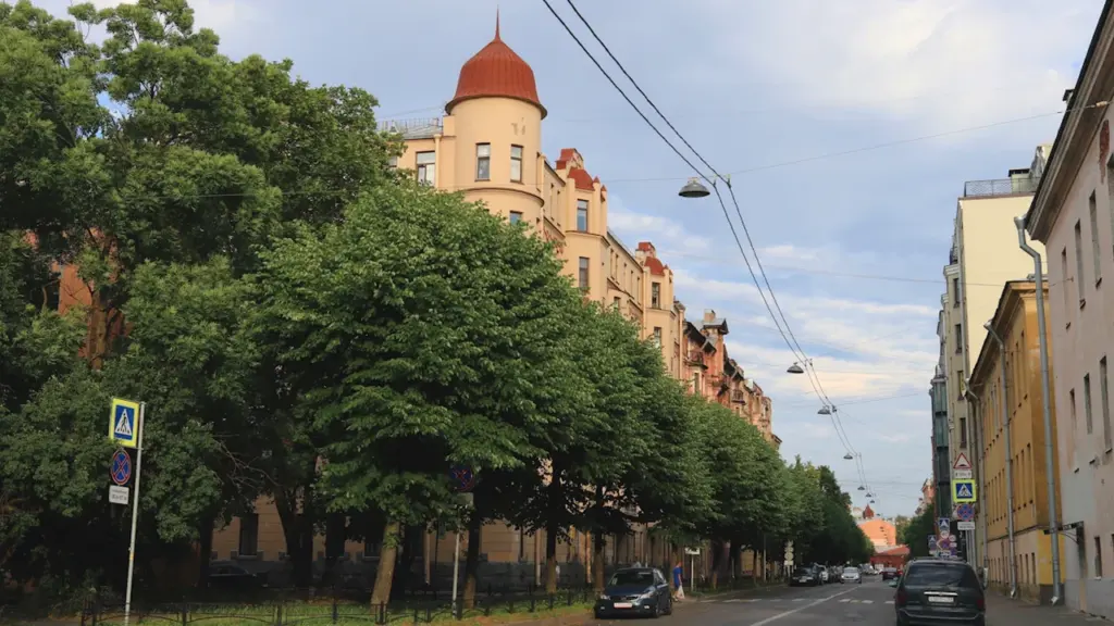Iela ar vēsturiskām jūgendstila ēkām un zaļiem kokiem Rīgas ielās.
