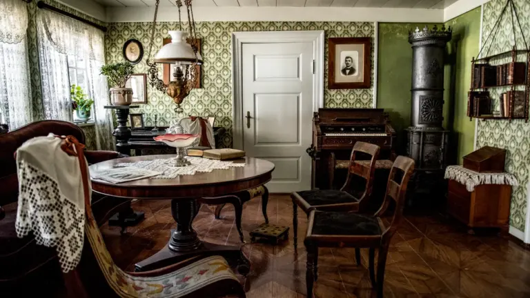 Mājīga veclaicīga istaba ar koka mēbelēm, kas atgādina vecvecāku mājas nostalģisko gaisotni.